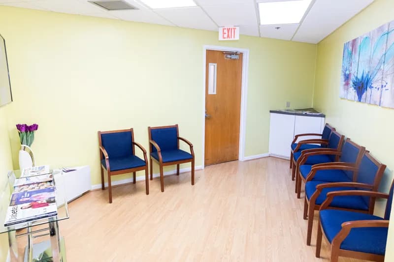 Reception area with seating, a check-in window, wall-mounted television and a brochure table