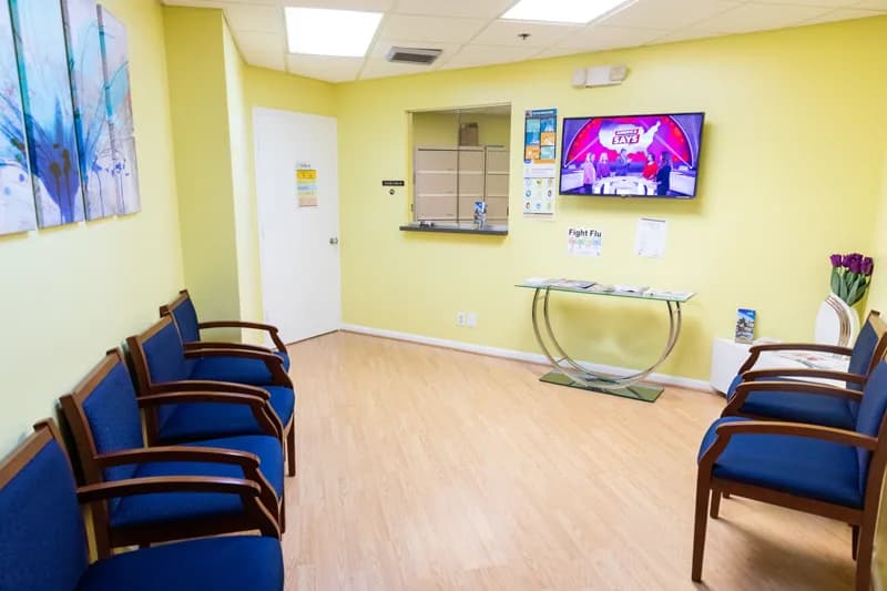 Waiting room with blue upholstered chairs, wooden flooring and framed artwork