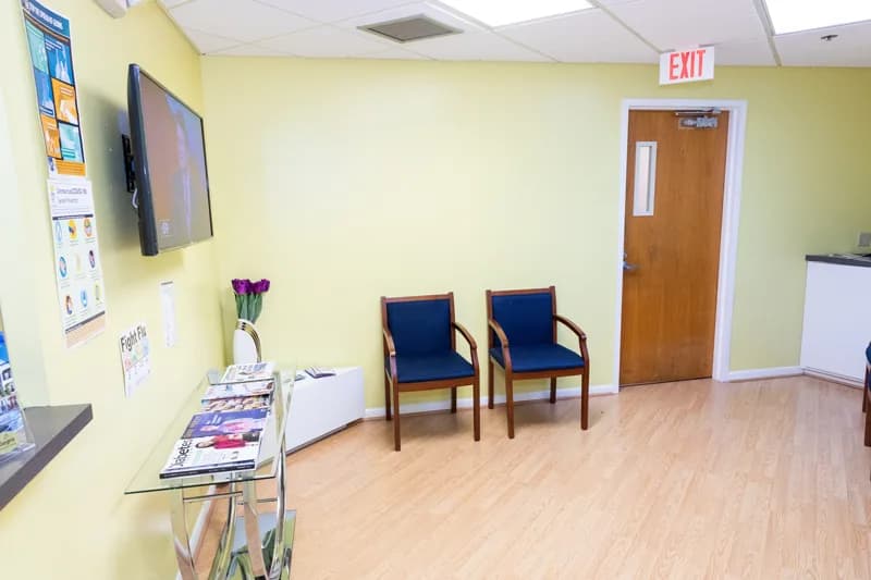 Second view of the waiting area showing health information posters, a brochure rack and seating